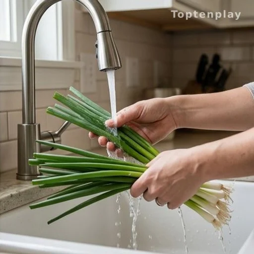 Hands rinsing green onions under a kitchen faucet