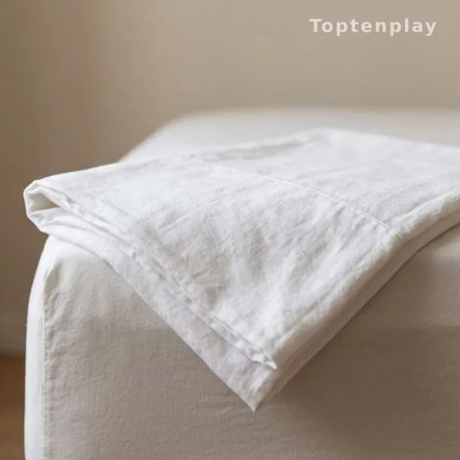 Close-up of folded cotton sheet texture on the edge of a bed