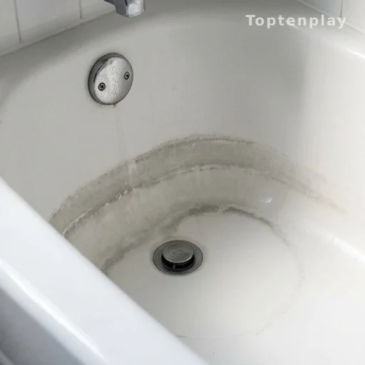 Porcelain bathtub with visible scum ring near drain caused by dirty mop water disposal