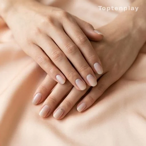 Close-up of hands with minimalist nail art on a soft pastel surface