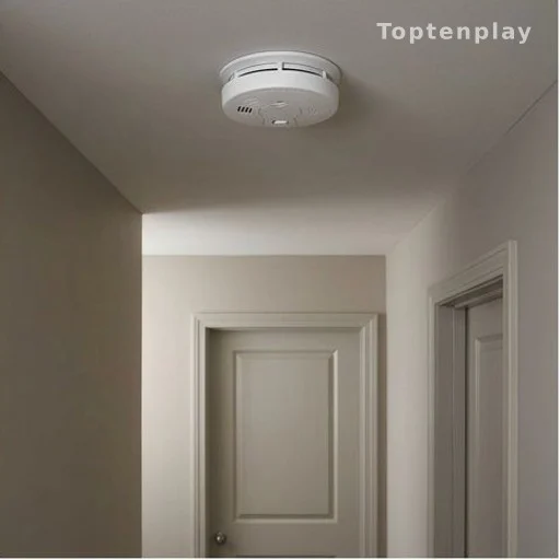 Smoke detector on home ceiling near bedroom door, residential fire safety equipment